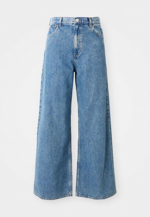 Høyhælte lyseblå vide denimjeans med frontknapp, glidelås og frontlommer på hvit bakgrunn.