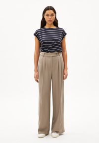 Navy striped t-shirt with a relaxed fit and short sleeves paired with high-waisted beige wide-leg trousers and white slip-on shoes.