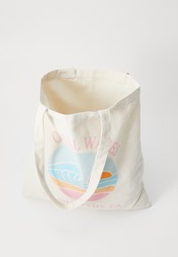 Sac en toile de coton beige avec un motif rond représentant des vagues en bleu, orange et rose, et le texte "Coral Waves" en rose.