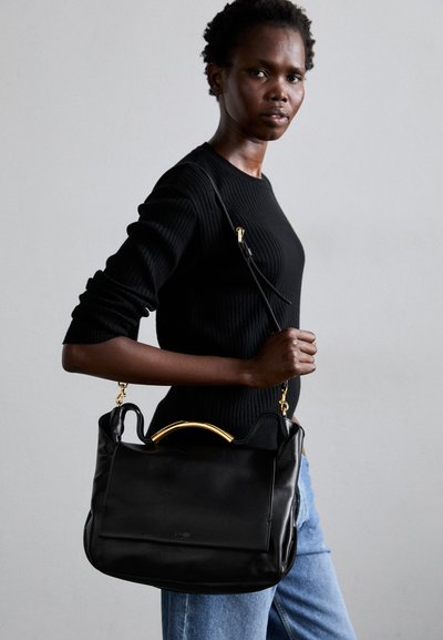 Schwarze Lederhandtasche mit goldfarbenen Akzenten am Griff, die eine glatte Oberfläche und ein strukturiertes Design aufweist. Wird mit einem Schulterriemen getragen.