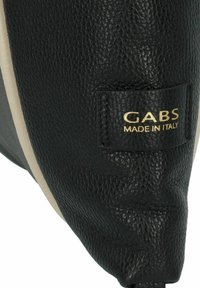 Zwarte leren tas met textuur en crèmekleurige accenten; beschikt over een gouden "GABS MADE IN ITALY" label dat aan één zijde is gestikt.