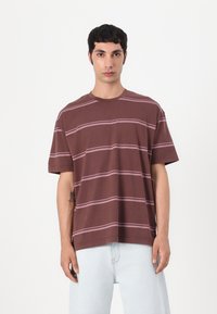 Brown short-sleeve t-shirt with wide pink horizontal stripes, featuring a crew neckline and a loose fit, shown against a white background.