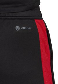 Tela negra con una franja vertical roja que presenta patrones sutiles, etiquetada "AEROREADY" con un ícono de globo, probablemente detalle de ropa deportiva.