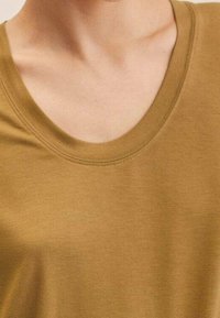 T-shirt à manches courtes vert olive avec un col rond, fabriqué en tissu lisse au toucher doux, présentant une coupe classique sans embellissements.