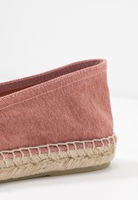 Espadrille rose en textile avec une semelle en jute tissé. Texture lisse et design minimaliste avec un dos plus haut et des coutures contrastantes.