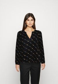 T-shirt de manga longa preta com decote em V, apresentando um padrão de motivos florais coloridos por toda a peça. Feita de tecido leve.