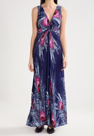 Sleeveless navy maxi dress with deep V-neck and pink, white, and yellow peacock feather print, worn with black shoes.