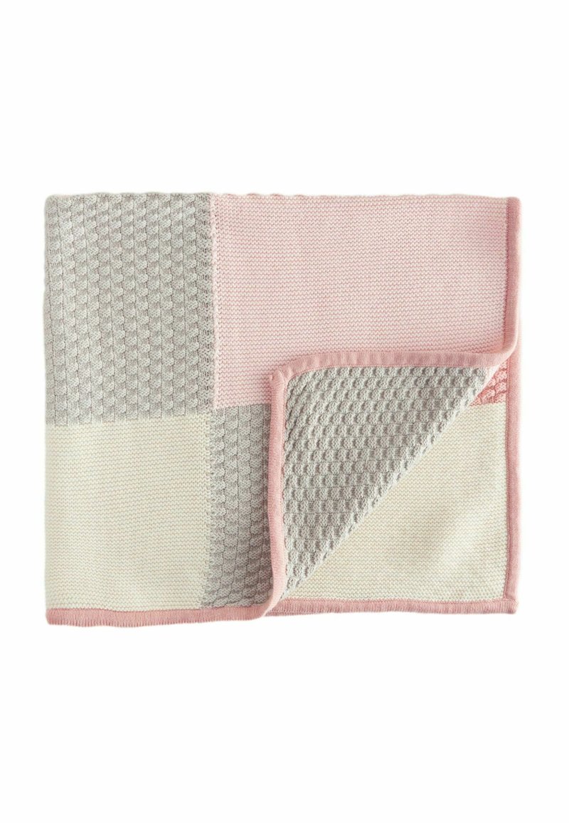 Knit blanket featuring a patchwork design in pale pink, light gray, and cream, with textured patterns and a smooth finish along the edges.