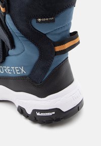 Wodoodporne buty trekkingowe z niebiesko-czarną tekstylną cholewką, oznaczeniem GORE-TEX, pomarańczowym paskiem akcentującym oraz wytrzymałą białą podeszwą Michelin.