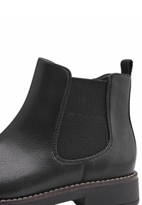 Musta nahkainen nilkkuri, jossa on joustavat sivupaneelit, teksturoitu pinta, pyöristetty kärki ja pinottu korko, jossa on kontrastivärinen tikkaus.