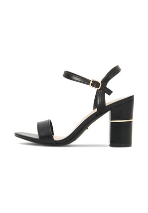 Schwarze Sandale mit offenem Zehenbereich, Blockabsatz, Knöchelriemen sowie goldfarbener Schnalle und Zierleiste am Absatz.