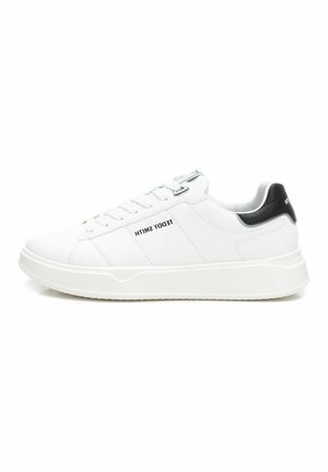 Zapatillas blancas de cuero con un acento en el talón negro, presentan un diseño de cordones, cuello acolchado y suela de goma texturizada. Nombre de la marca en el lado.