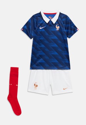 Blauw en zwart gestreept voetbalshirt met korte mouwen, witte kraag, witte short en een enkele rode sok, allemaal met gouden Nike- en haanlogo's.