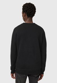 Black sweatshirt with a round neck, long sleeves, and ribbed cuffs and hem. Features a smooth texture and minimalistic design.