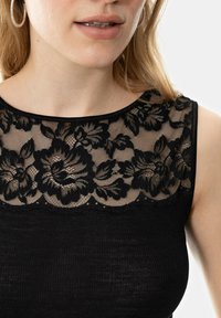 Black top featuring a floral lace neckline with a scalloped edge. The main fabric has a ribbed texture, creating contrast with the lace.