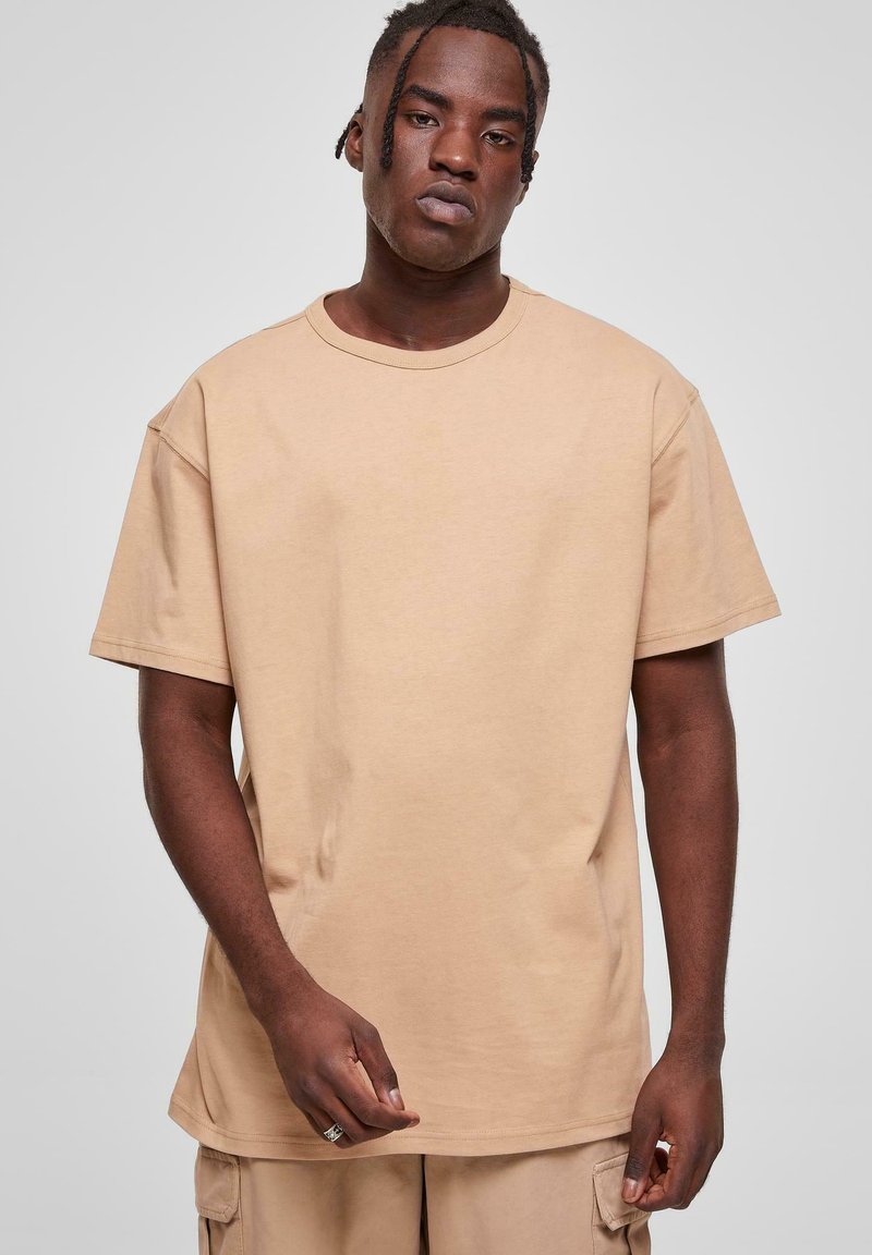 Tricou din bumbac bej, cu decolteu rotund și mâneci scurte. Croială lejeră, cu o textură fină și un design simplu. Fără modele sau accente vizibile.