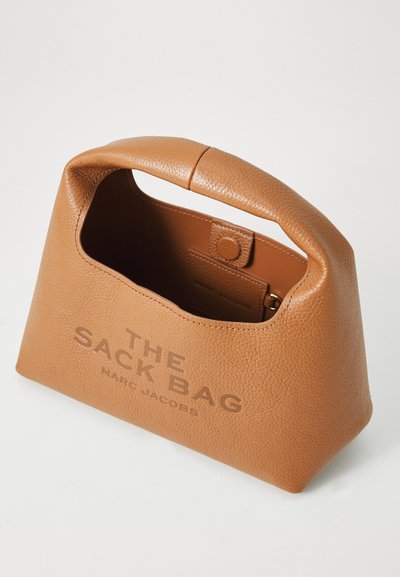 Helle Ledertasche mit rundem Griff, texturiertem Oberflächen und geprägtem Branding. Der offene Rand gibt einen Blick auf das braune Innere mit einem Druckknopfverschluss.