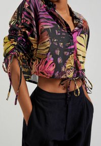 Korte mouwen, cropped button-up shirt in zwart met een kleurrijke tropische bladerenprint, voorzien van gathered details en strikken bij de mouwen.
