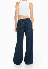 Szerokie spodnie dżinsowe w kolorze granatowym o luźnym kroju, z elastycznym pasem i dwoma tylnymi kieszeniami. Gładka tekstura i casualowy design.