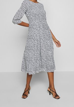 Vestido de estampado floral, con longitud hasta la rodilla y mangas tres cuartos. Colores negro y blanco, con cintura ceñida, falda acampanada y tejido texturizado.