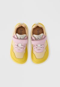 Κίτρινα και ροζ παιδικά αθλητικά παπούτσια με υφασμάτινο άνω μέρος με υφή, καουτσούκ σόλα, ρυθμιζόμενο λουράκι βέλκρο και διακριτικό λογότ υπο στη φτέρνα.