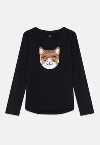 Svart långärmad tröja med ett leende kattansikte gjort av bruna och vita paljetter i mitten fram.