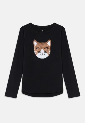 T-shirt à manches longues noire avec un visage de chat souriant fait de paillettes brunes et blanches au centre avant.