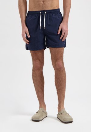 Marine zwemshorts met een trekkoord in de taille, zijzakken en een gespleten zoom; gemaakt van lichtgewicht stof met een gladde textuur.