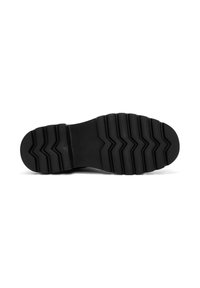 Suela de zapato negra con un patrón de relieve en zigzag profundo para mayor agarre, exhibida sobre un fondo blanco, con la suela hacia arriba.