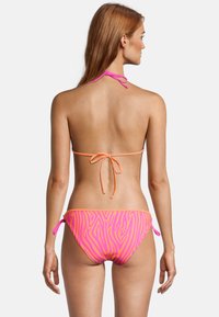 Bikini avec un motif zèbre noir et rose néon, avec de fines lanières au cou et sur les côtés, et un design taille basse.