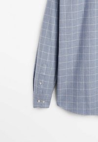 Chemise à carreaux bleu clair avec boutons, manches longues, motif à grille blanche, tissu doux et poignets à boutons.