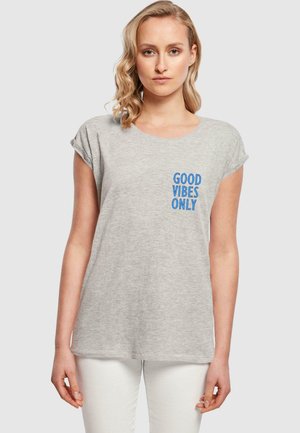 Graues Baumwoll-T-Shirt mit umgeschlagenen Ärmeln, das auf der linken Brustseite blauen Text "GOOD VIBES ONLY" zeigt. Einfaches, lässiges Design.