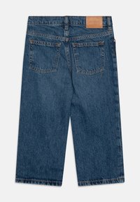 Temno modri široki jeans iz jeansa z gladko teksturo. Vključuje dve zadnji žep in svetlo rjavo usnjeno oznako na pasu.