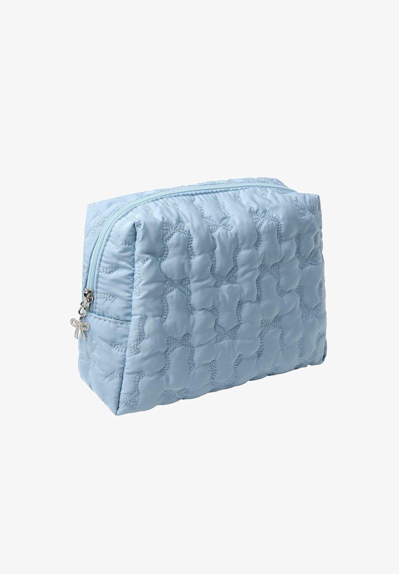 Ljusblå kviltad kosmetikväska med dragkedjestängning, prydd med ett subtilt mönster av rosetter och en dekorativ silverberlock på dragkedjan.