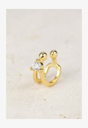 Anillo de oro con un diseño abierto único, que presenta una gema redonda y transparente en la parte frontal y acentos redondeados a los lados.