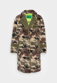 Płaszcz z futra sztucznego w kamuflażowym wzorze w kolorach brązowym, zielonym i czarnym. Posiada zielony kołnierz, naszywaną kieszeń oraz zapięcie z przodu.