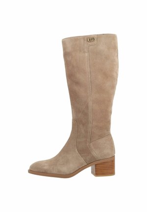 Stivale alto beige in camoscio con tacco impilato in legno e piccolo logo vicino al bordo superiore, mostrato di profilo su sfondo bianco.