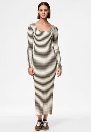 Robe maxi à rayures longues et à manches en beige avec des rayures noires, dotée d'un décolleté en scoop. Le modèle porte des baskets marron pour un look décontracté.