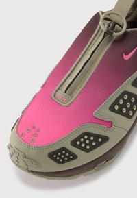 Nike-sneaker med gradientdesign fra rosa til lilla, med glidelås, teksturerte grønne detaljer og karakteristiske perforerte detaljer.