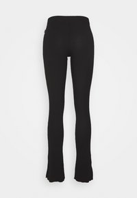 Svarta utsvängda leggings med en åtsittande design, tillverkade av ett elastiskt material. Har hög midja och utsvängd stil vid fållen.