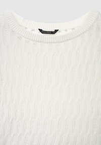 Maglione bianco lavorato a maglia con motivo a coste, scollo rotondo e etichetta del logo visibile. Texture morbida e aspetto leggero.