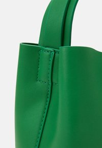 Borsa a tracolla verde in pelle con texture liscia, lati dritti e cuciture coordinate. Presenta manici robusti nella parte superiore per un facile trasporto.