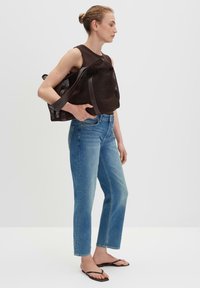 Bruine netstof boodschappentas met brede hengsels, blauwe spijkerbroek met een rechte snit en zwarte teenslippers. Soepele texturen, minimalistisch ontwerp.
