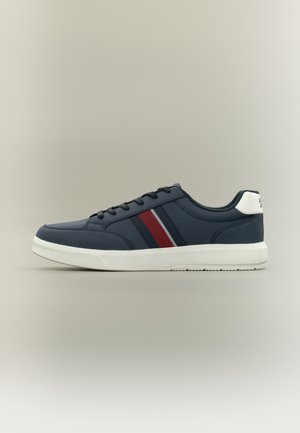 Tums zils zems augstums sporta apavu ar baltu zoli, sarkaniem un tumši zilas svītras detaļām sānos, melnām auklām un baltu papēža cilpiņu.