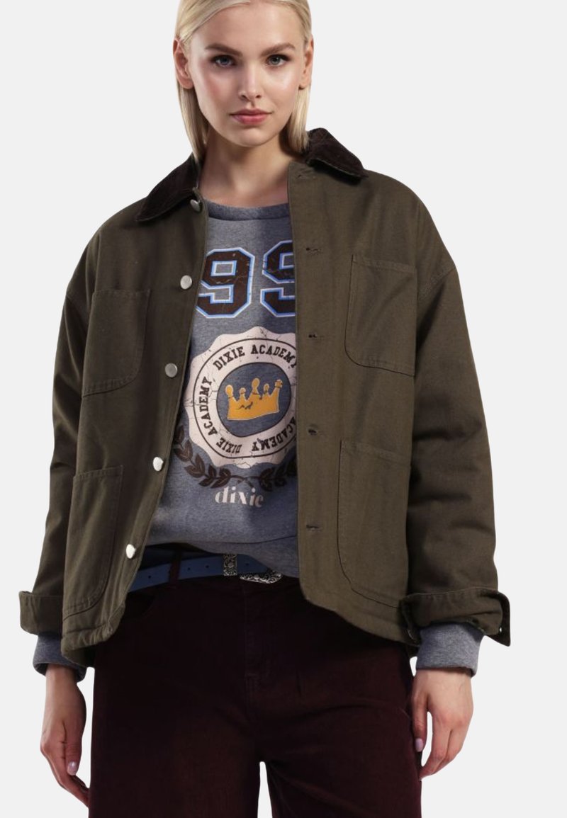 Olivengrøn jakke med et corduroy-krave, store frontlommer og sølvknapper, lagdelt over en grå sweatshirt med grafiske designs.