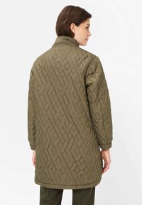 Olivgrüne gesteppte Jacke mit hohem Kragen, langen Ärmeln und geometrischem Muster. Glatte Textur und längerer Schnitt.