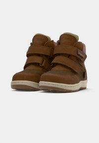 Zapatos altos de cuero marrón con dos correas de Velcro, paneles texturizados, acentos beige y suela de goma.