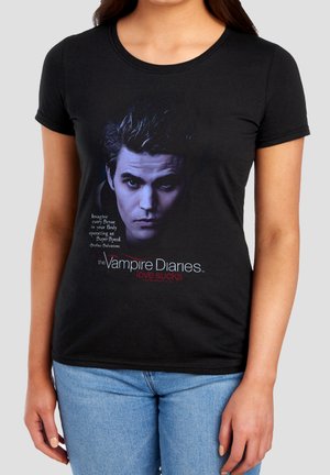 Woman wearing black T-shirt with portrait of a man and text "The Vampire Diaries love sucks" and a quote from Stefan Salvatore.