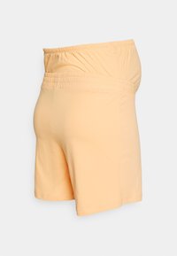 Calções de maternidade em algodão pêssego suave, com cintura elástica e uma silhueta relaxada. Apresentam uma textura lisa e um design de bainha simples.