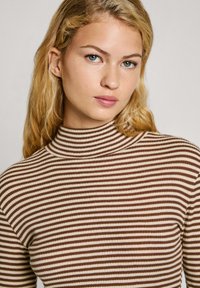 Jersey de cuello alto a rayas marrón y crema con textura acanalada, diseño ajustado y mangas largas, que destaca por su alto cuello.